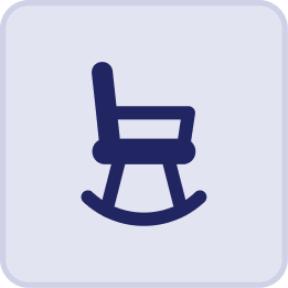 Dark blue icon of a rocking chair on a light background, surrounded by a rounded square border—evoking the cozy ambiance of the Hatteras Grand Room at Sunset Inn.