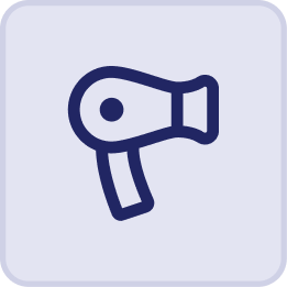 A simple, dark blue line drawing of a hair dryer is centered on a light gray rounded square background—evoking the relaxing comfort found at the Hatteras Grand Room Sunset Inn.
